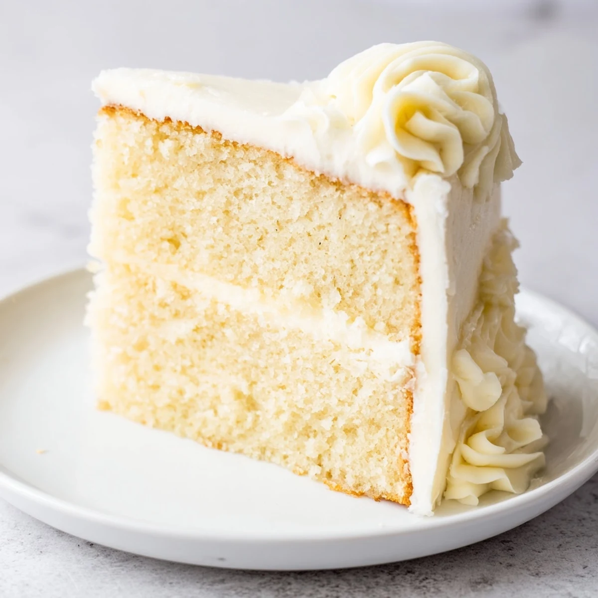 Fluffy white Frosted Delight Vanilla Cloud cake, stacked high with creamy vanilla frosting and ready to serve.