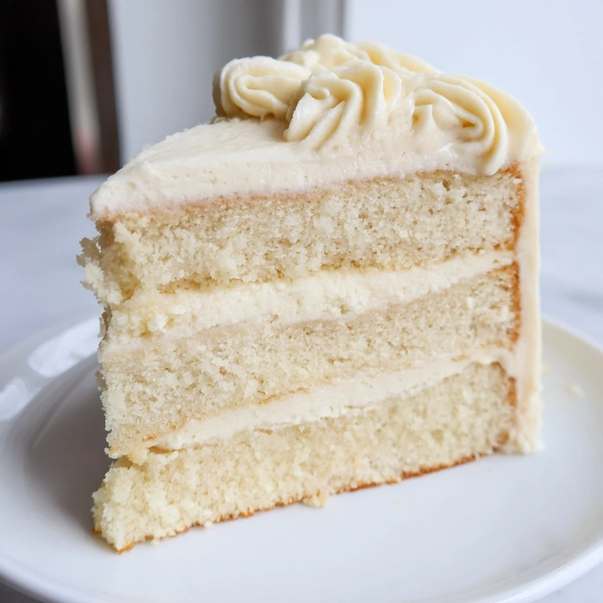 A slice of light and airy Frosted Delight Vanilla Cloud cake with smooth vanilla frosting looks delightful.