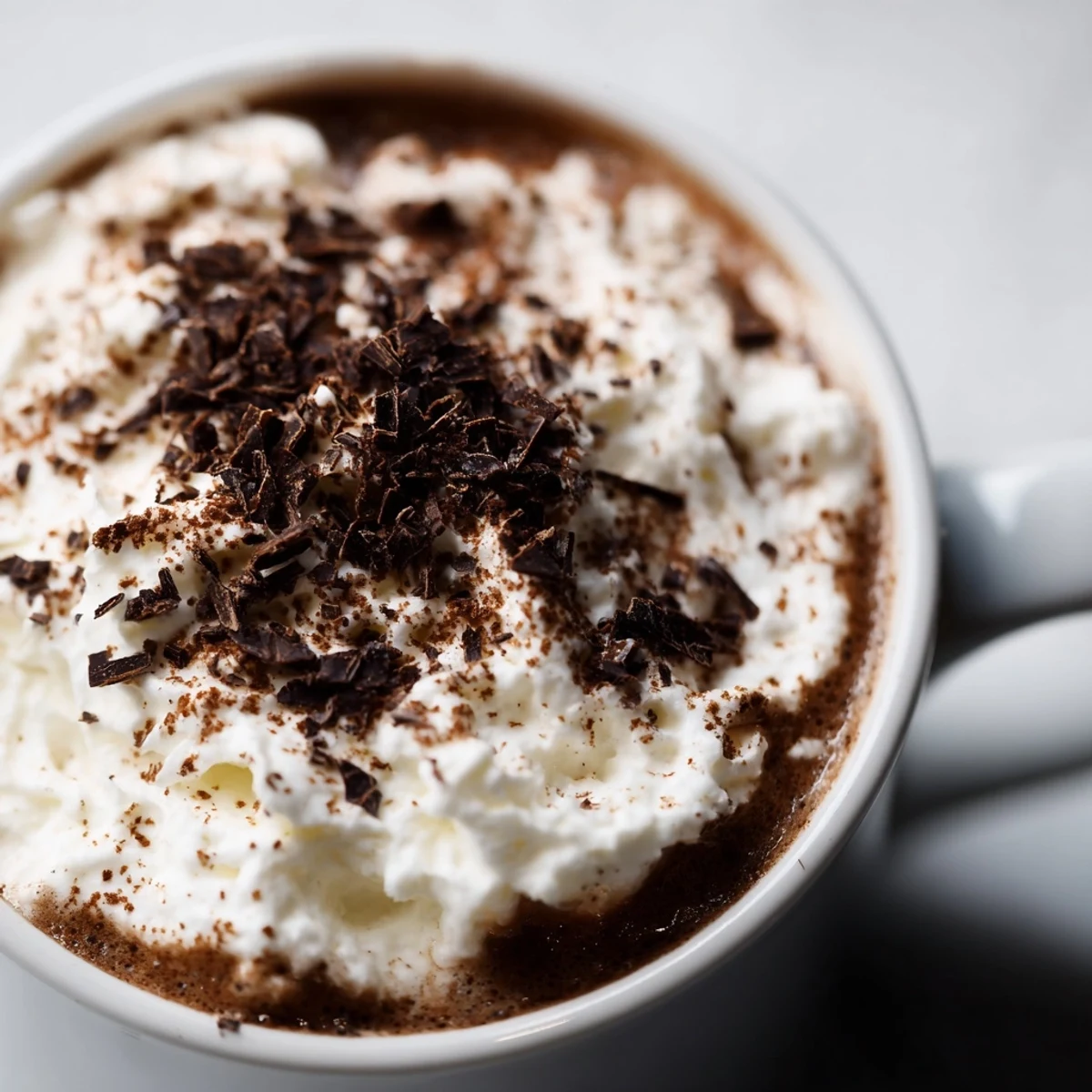 Steaming mugs of Winter Spice Mocha Whisper topped with fluffy whipped cream and a cinnamon dusting.