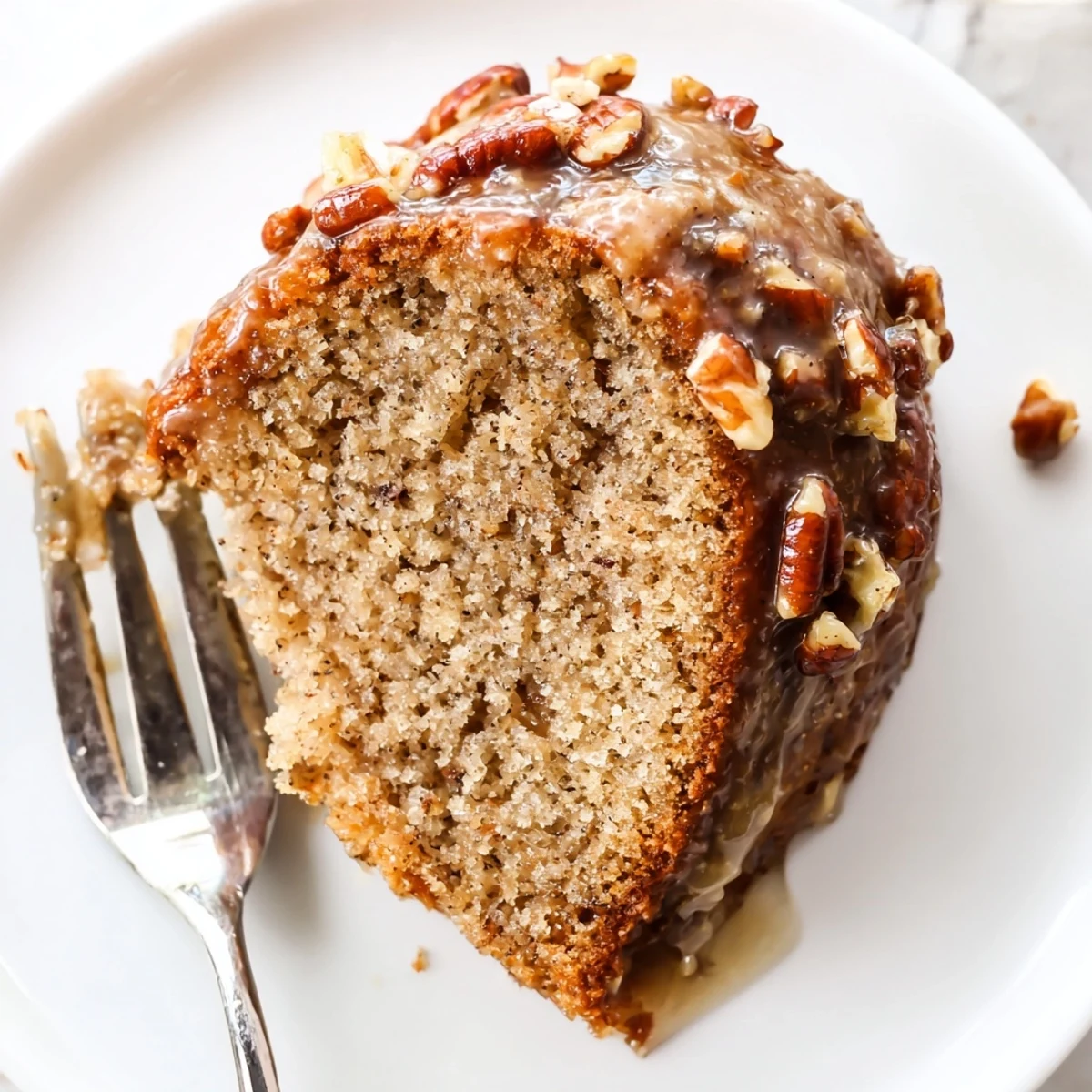 Freshly baked Winter Spice Maple Dream cake sliced into squares, drizzled with maple syrup and topped with toasted pecans on a rustic wooden board.