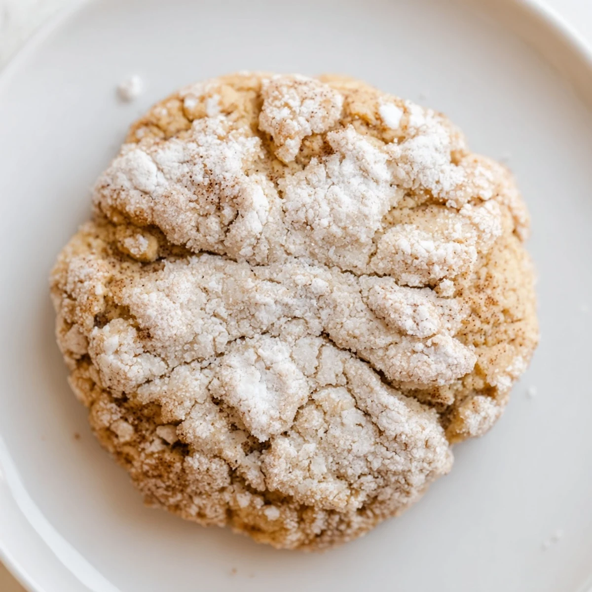 Freshly baked Holiday Glow Brown Sugar Snow Keto Cookies are dusted with powdered sweetener on a parchment-lined tray.