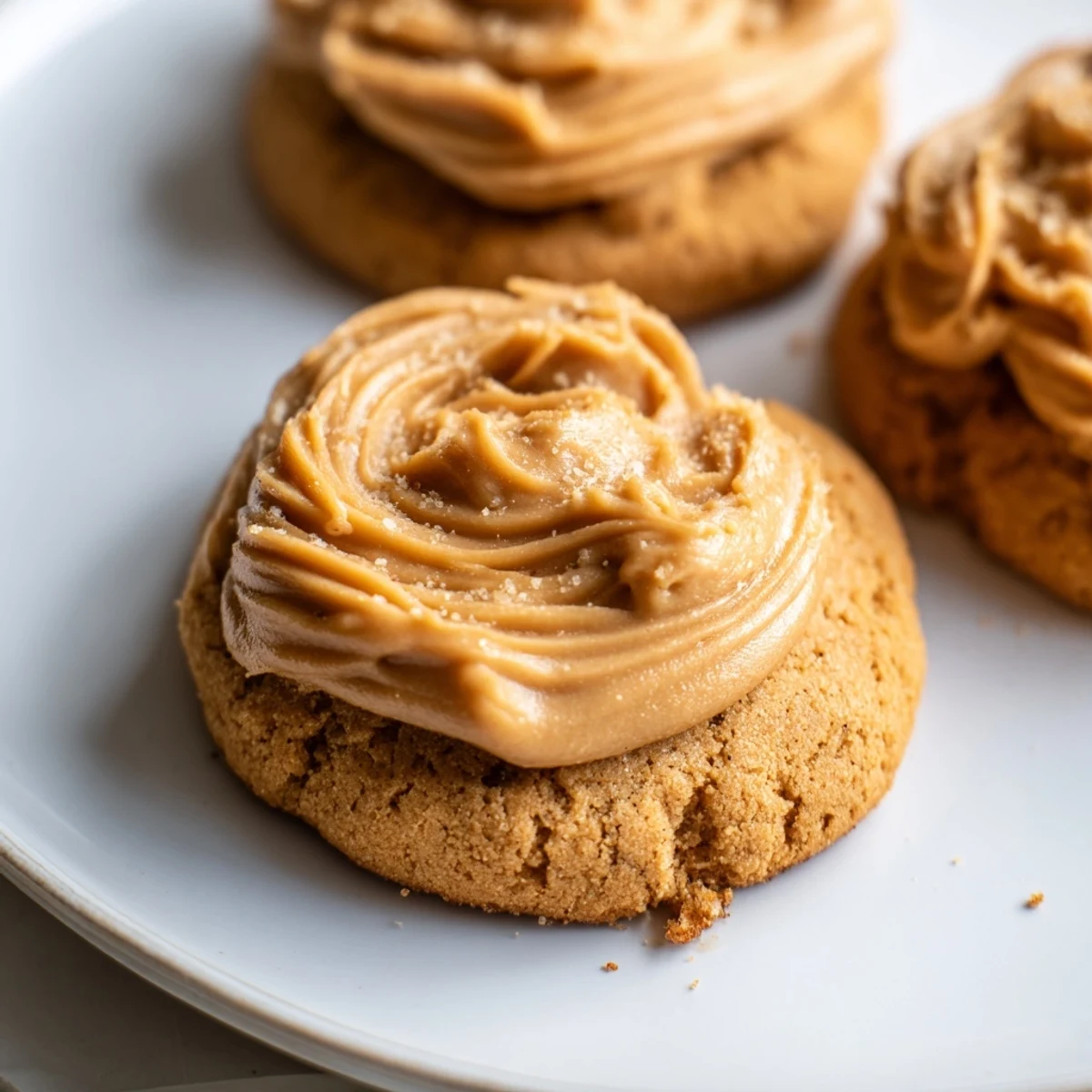 Sugary, glossy caramel frosting being piped onto warm Holiday Glow Caramel Frost Vegan Cookies for a festive dessert tray.