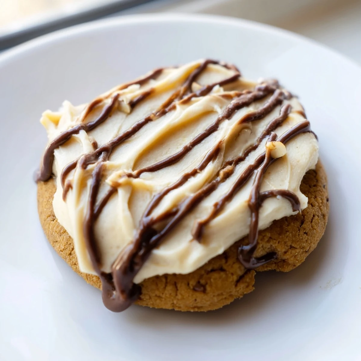 Golden-brown Frosted Delight Hazelnut Drizzle Keto Cookies on a rustic wooden board, with creamy frosting and a glossy drizzle.