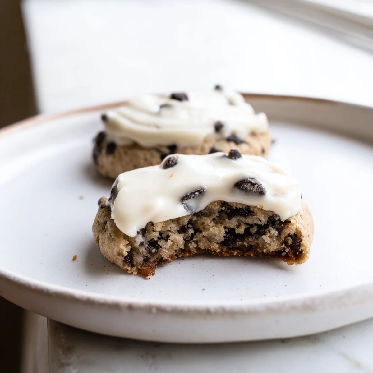 A close-up of Frosted Delight Mocha Whisper Keto Cookies shows a soft-baked texture, crumbly almond flour edges, and melted sugar-free chocolate chips.