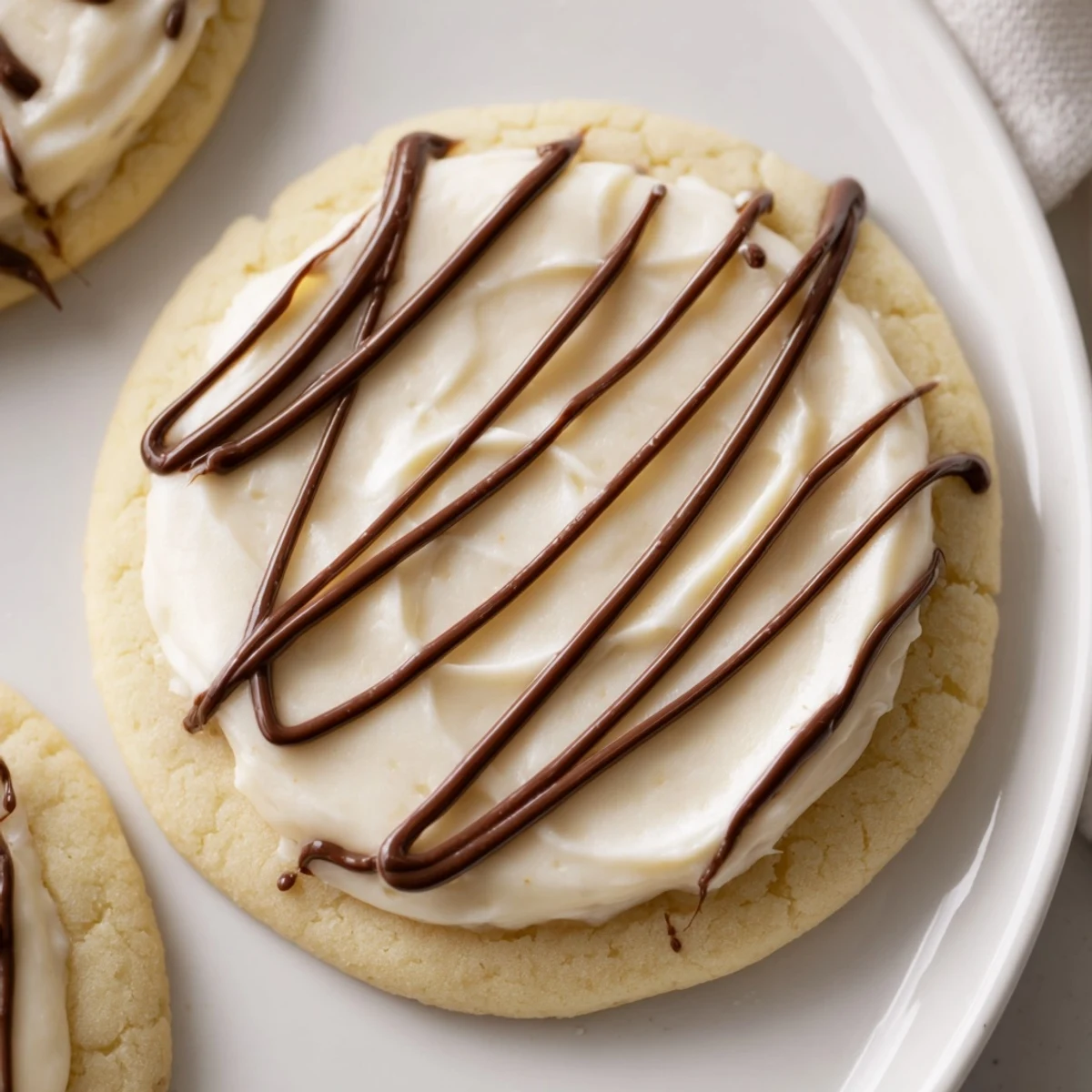 A close-up of frosted delight hazelnut drizzle sugar cookies on a rustic wooden board, with creamy vanilla frosting and a glossy chocolate hazelnut swirl.