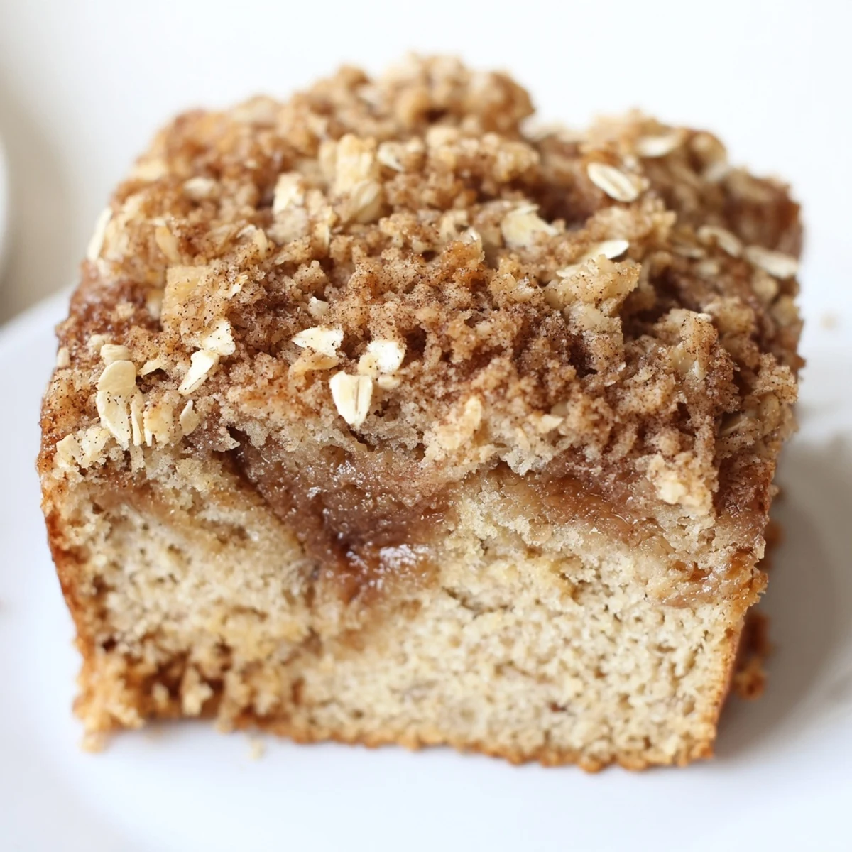 Freshly baked Snowy Day Cinnamon Drift coffee cake with a crispy oat topping sits on a rustic wooden table.