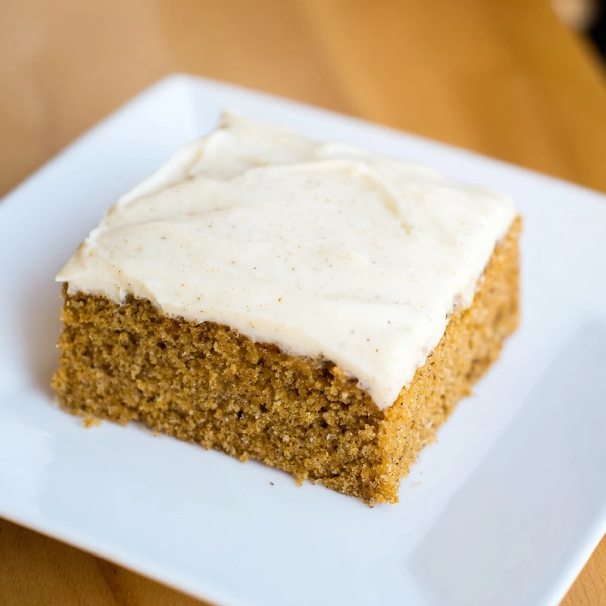 A slice of Frosted Delight Ginger Spice served with hot tea, featuring moist crumb and velvety frosting.