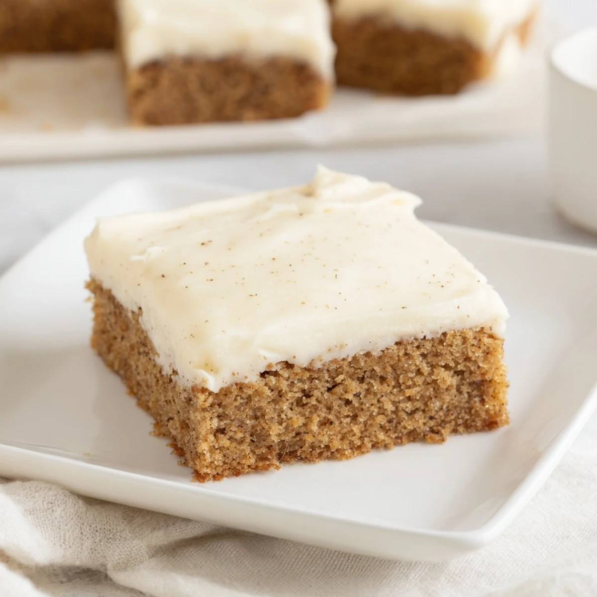 Gluten-free Frosted Delight Ginger Spice cake topped with creamy frosting and dusted with ground ginger on a white plate.