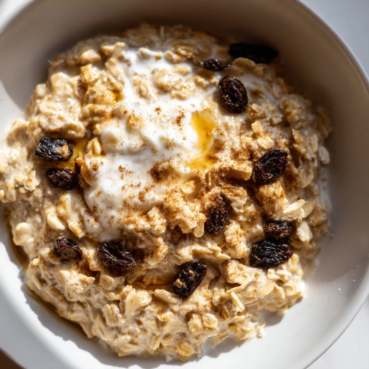 A steaming bowl of Winter Warmth Vanilla Cloud Oatmeal Raisin studded with raisins and a dollop of whipped cream for breakfast.