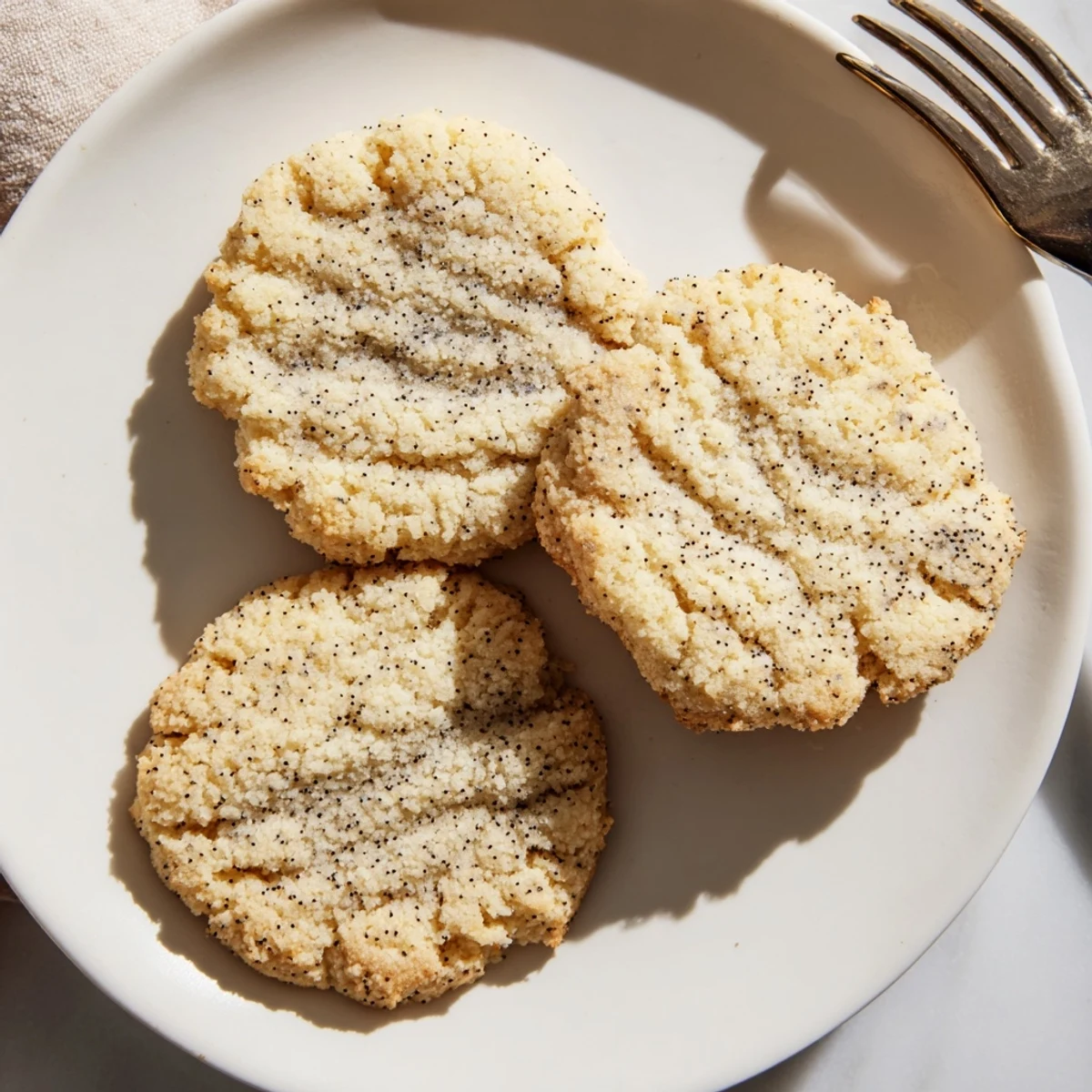 Freshly baked Keto Vanilla Bean Butter Cookies with visible vanilla specks on a rustic wooden table.