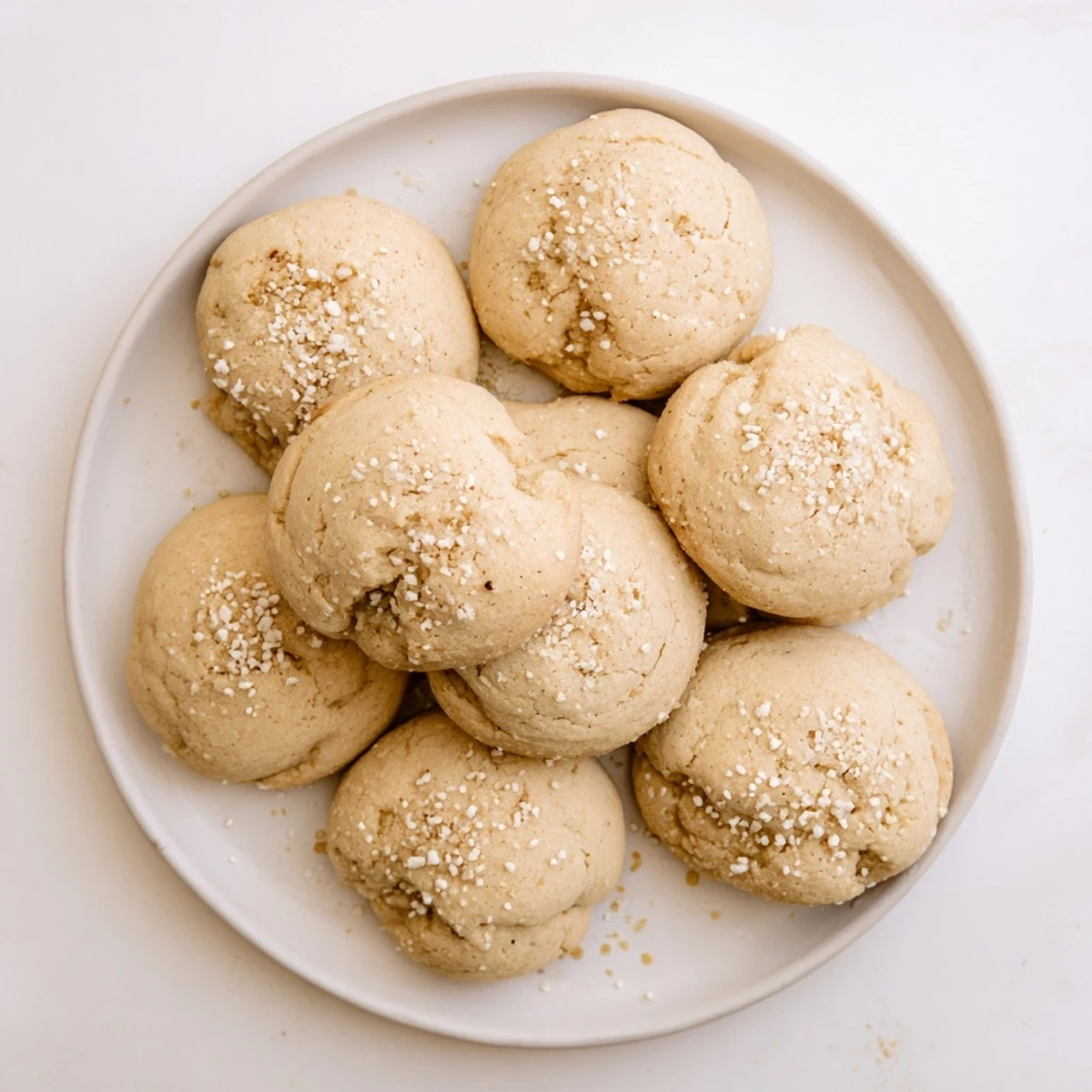 Ricotta Honey Sugar Cookies stacked on a white plate with a honey dipper and tea cup, ready for teatime.