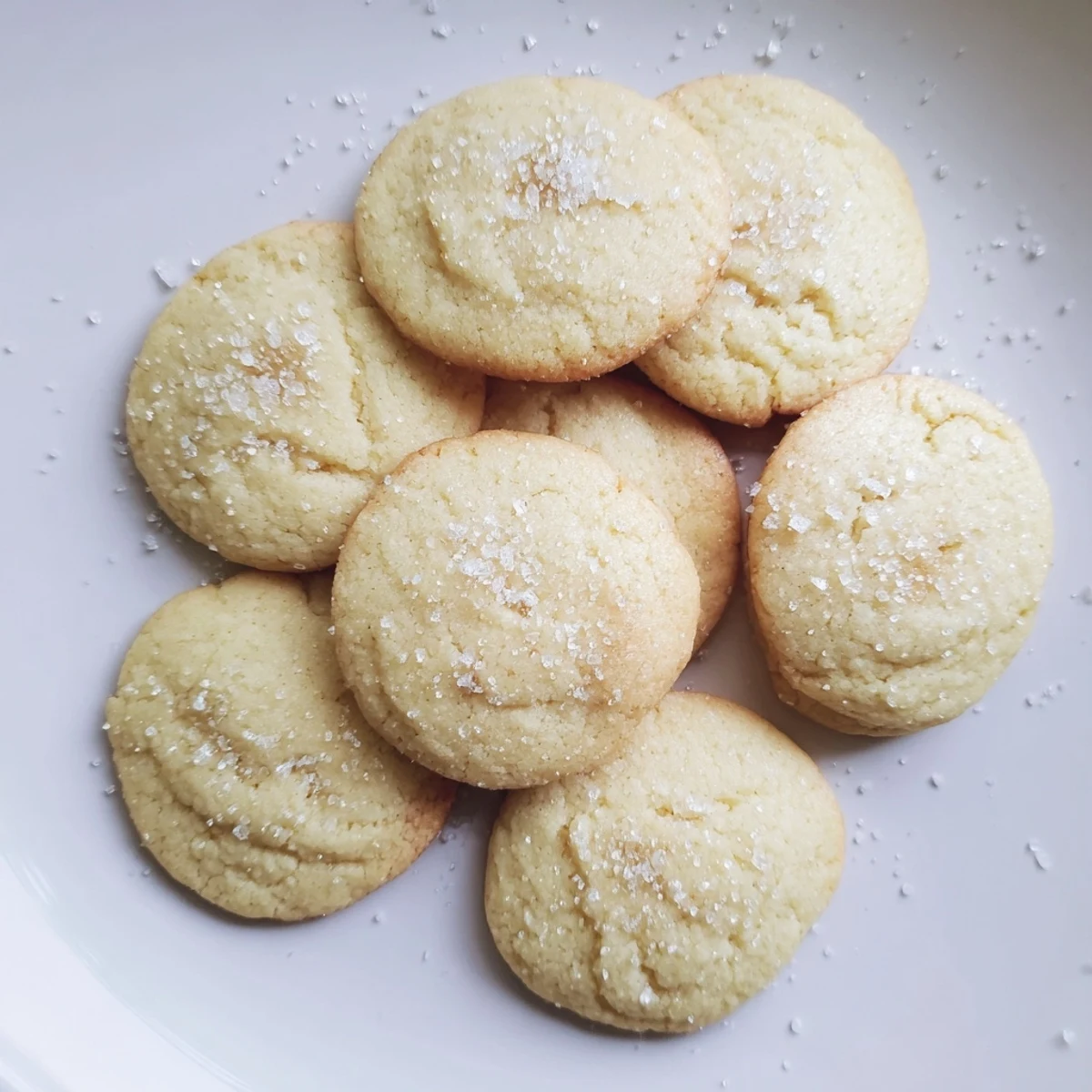 Golden-brown Ricotta Honey Sugar Cookies with a cracked top and coarse sugar crystals glistening on a rustic wooden board.