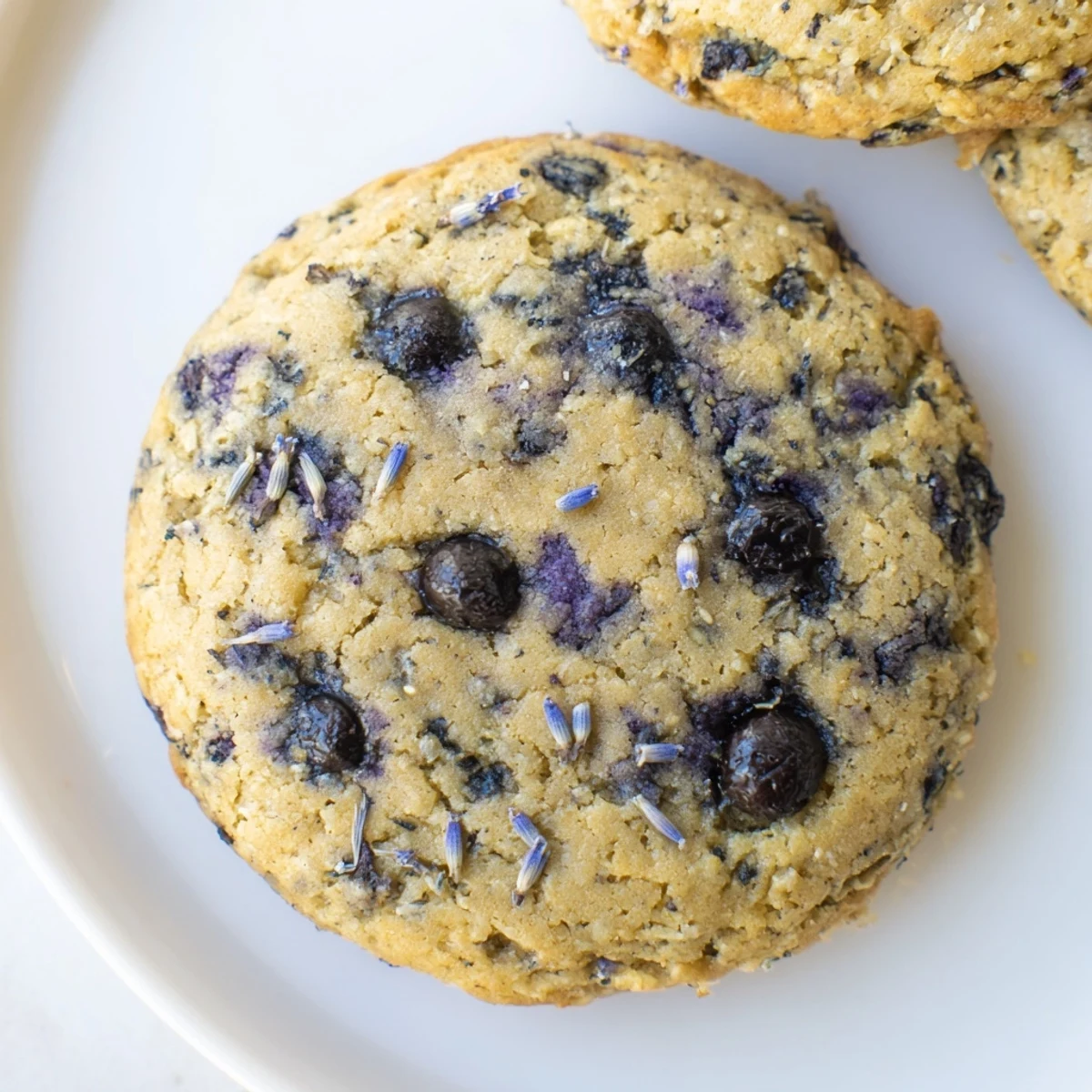Stack of chewy vegan blueberry lavender chocolate chip cookies dotted with juicy berries and floral lavender bits