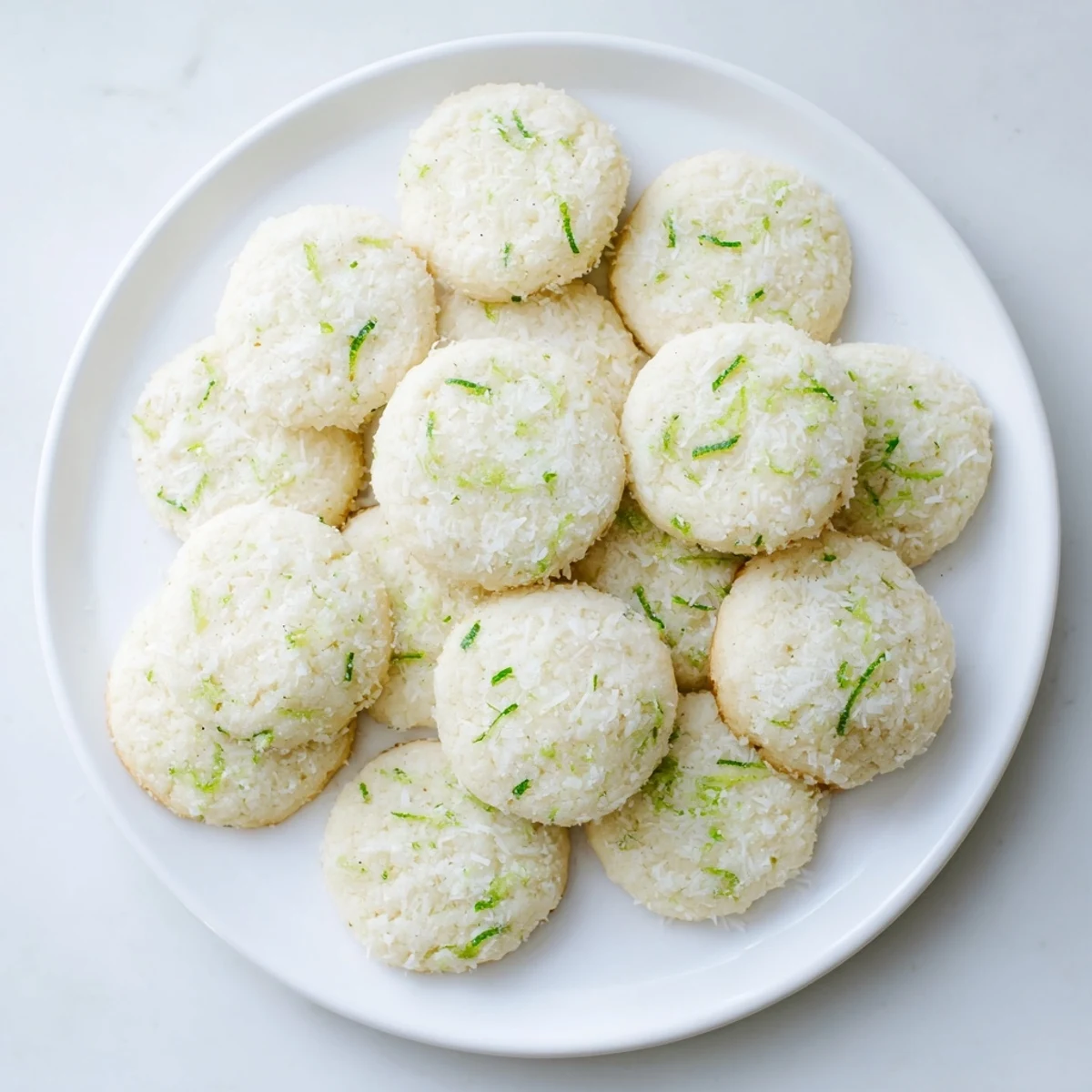 Close-up of soft gluten-free coconut lime sugar cookies flecked with green lime zest and white coconut