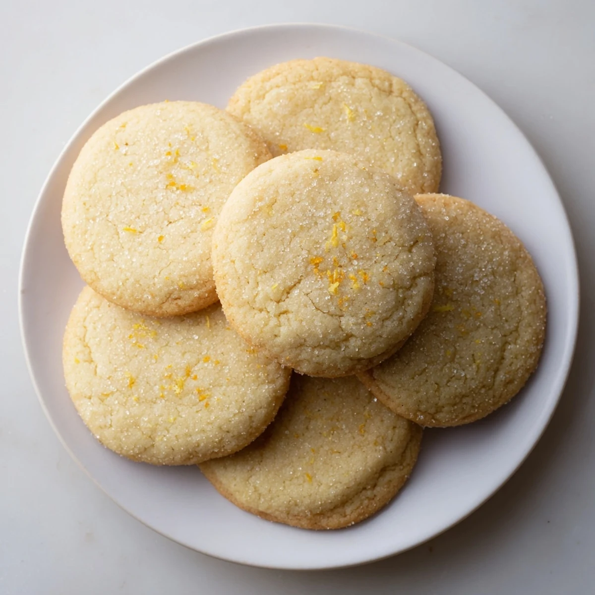 Soft gluten-free lemon honey sugar cookies with sugary coating on a white plate