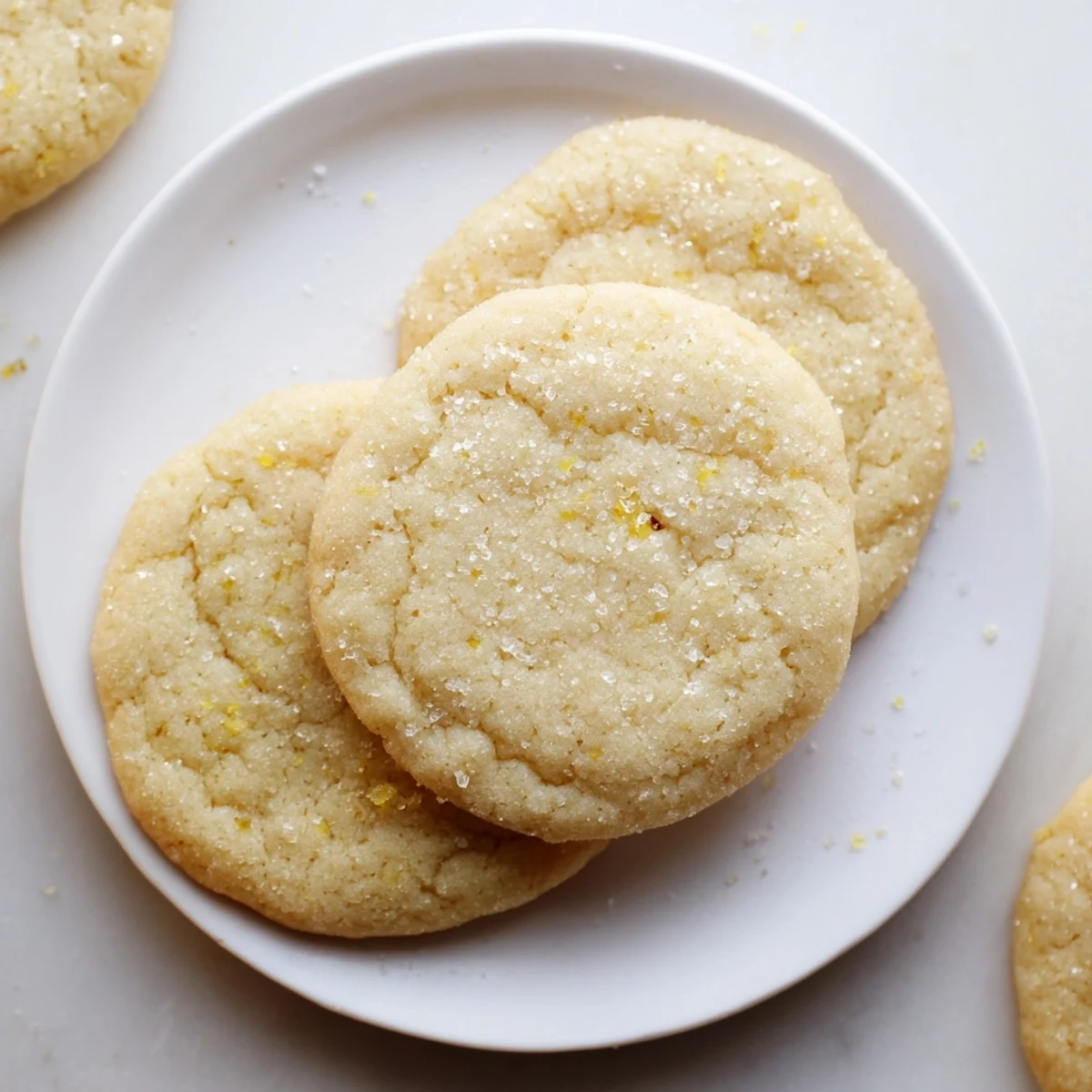Golden gluten-free lemon honey sugar cookies stacked on a rustic wooden cutting board