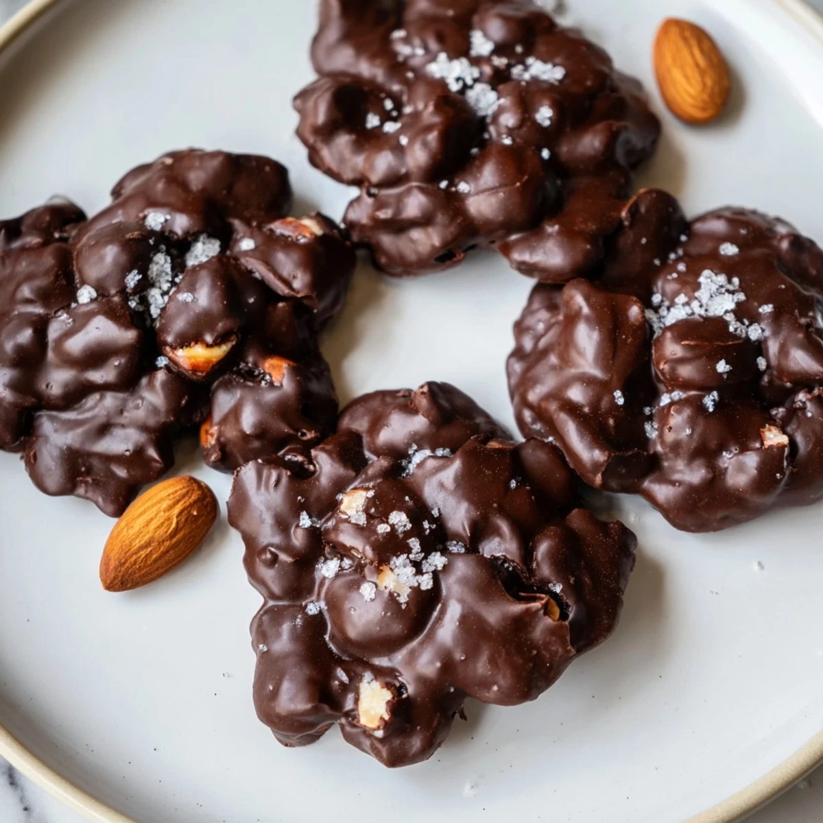 Keto dark chocolate almond cluster cookies arranged on parchment paper with flaky sea salt sprinkled on top