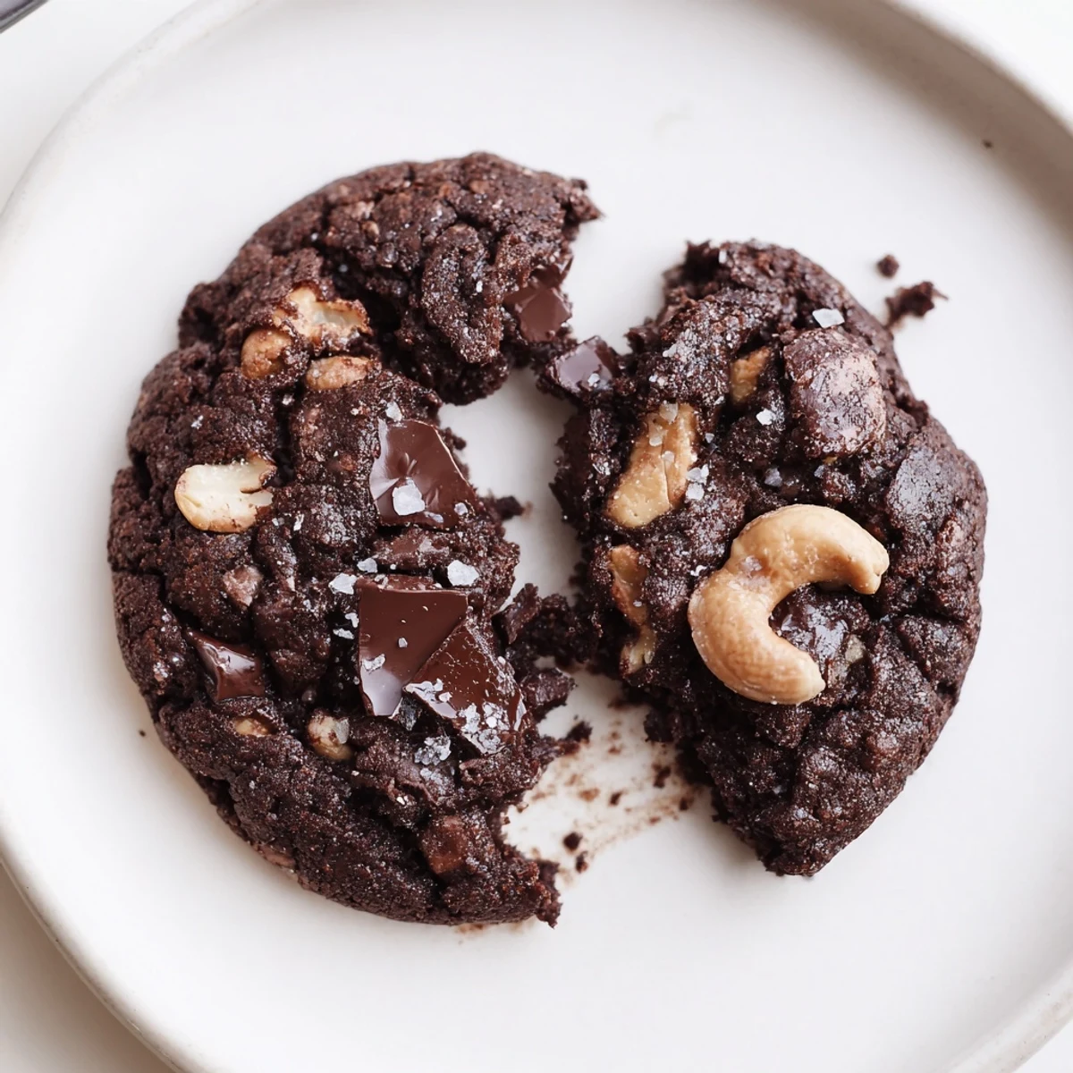 Stacked Gluten-Free Dark Chocolate Cashew Crunch Cookies beside a glass of cold milk