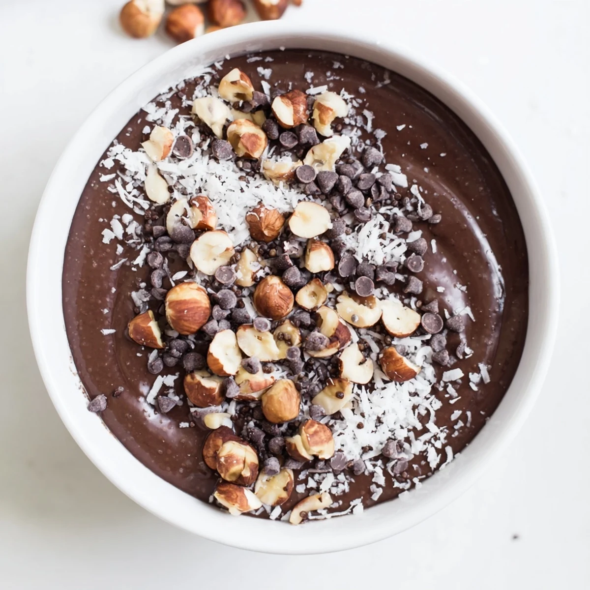 Creamy chocolate hazelnut coconut protein chia cream topped with roasted nuts and shredded coconut