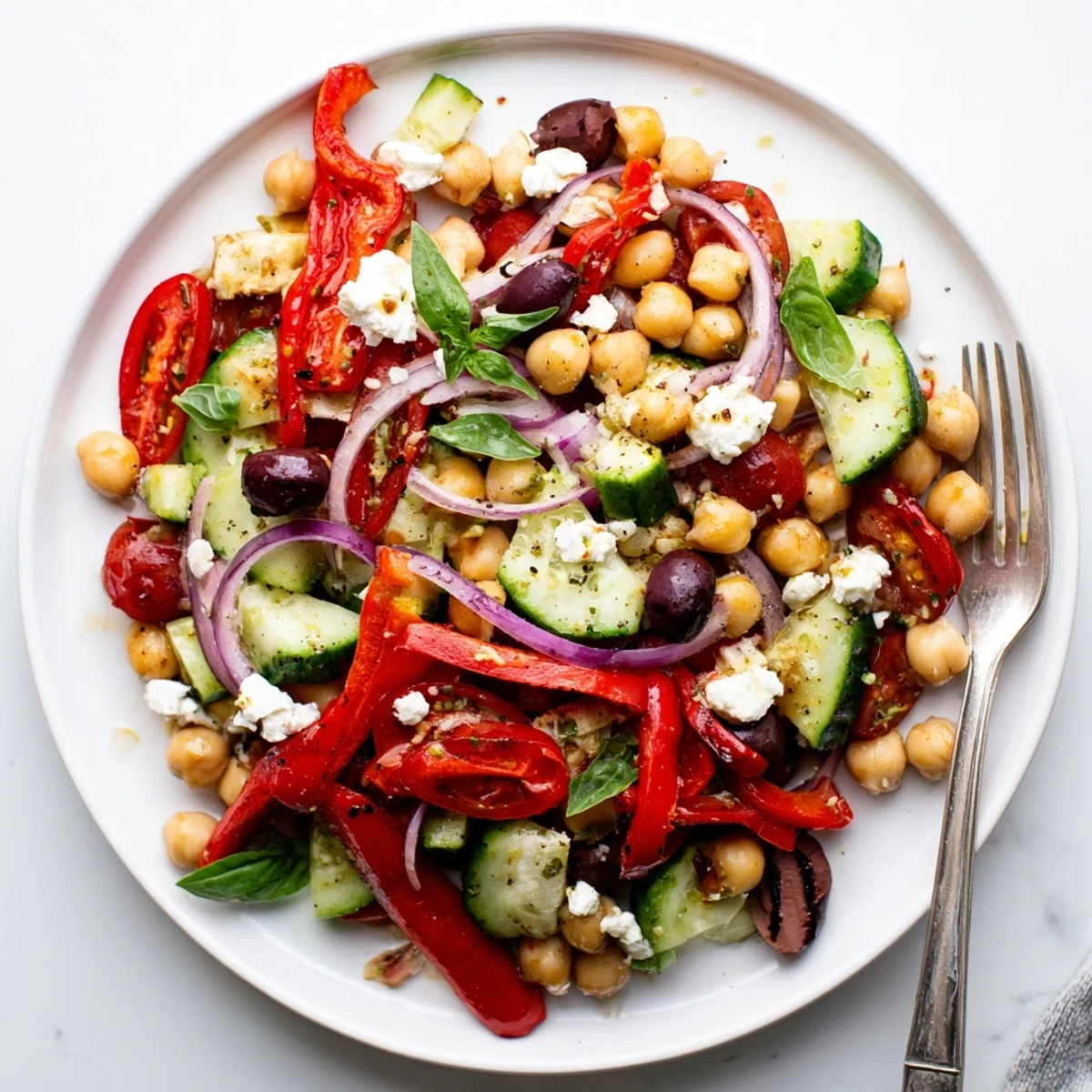 Bowl of Mediterranean chickpea roasted pepper basil salad drizzled with lemon dressing