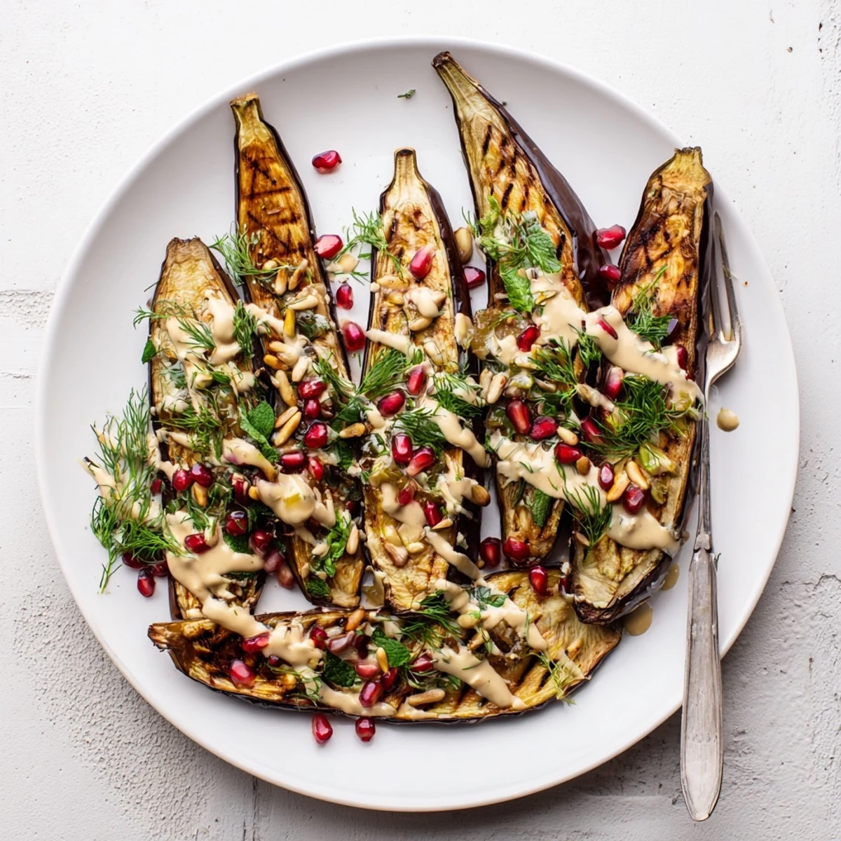 Mediterranean roasted eggplant with velvety lemon tahini sauce sprinkled with pine nuts and parsley