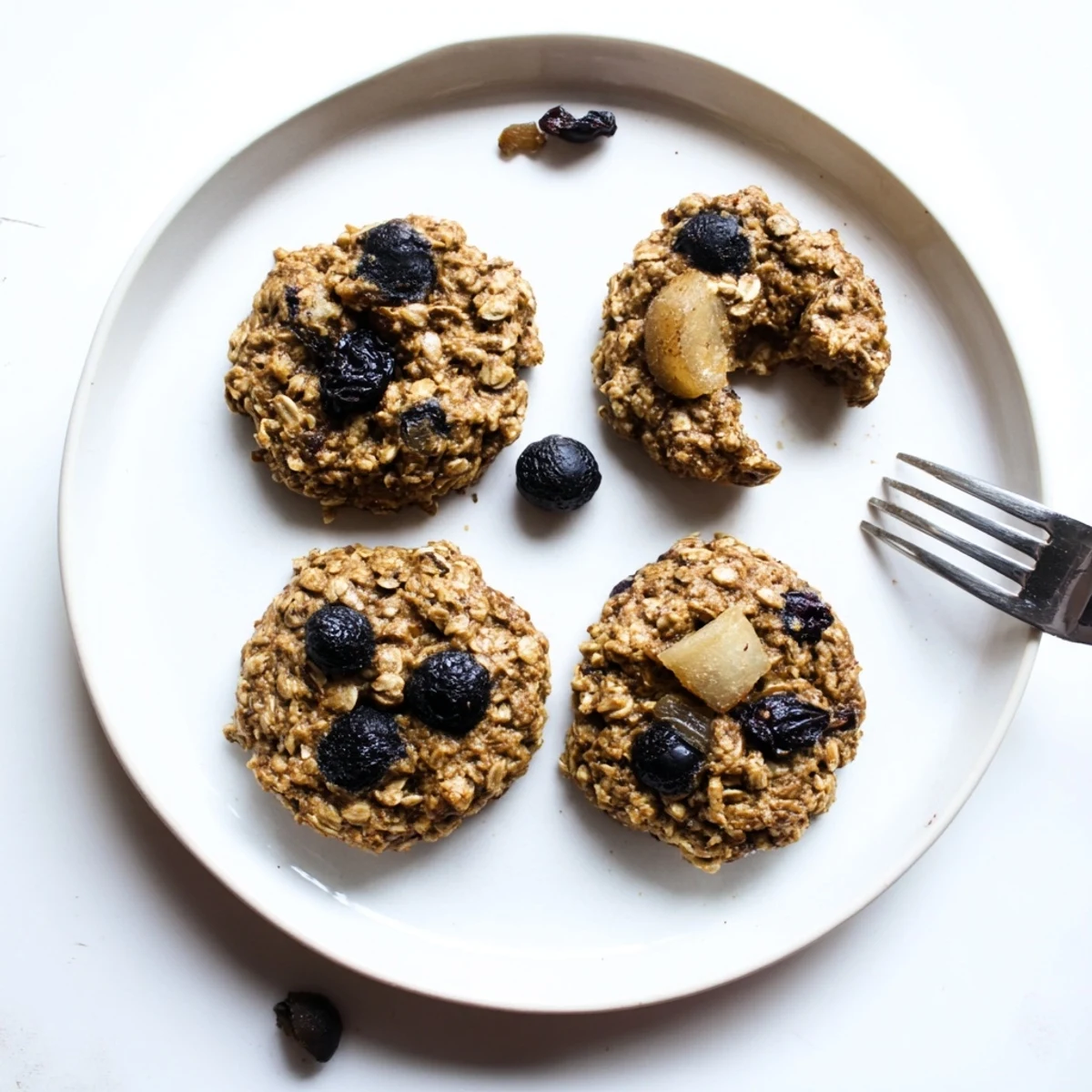 Warm Vegan Blueberry Pear Oatmeal Raisin Cookies cooling on parchment, juicy blueberries.