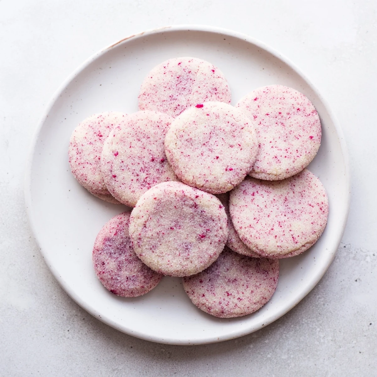Crispy-edged vegan vanilla hibiscus sugar cookies dusted with hibiscus sugar alongside herbal tea