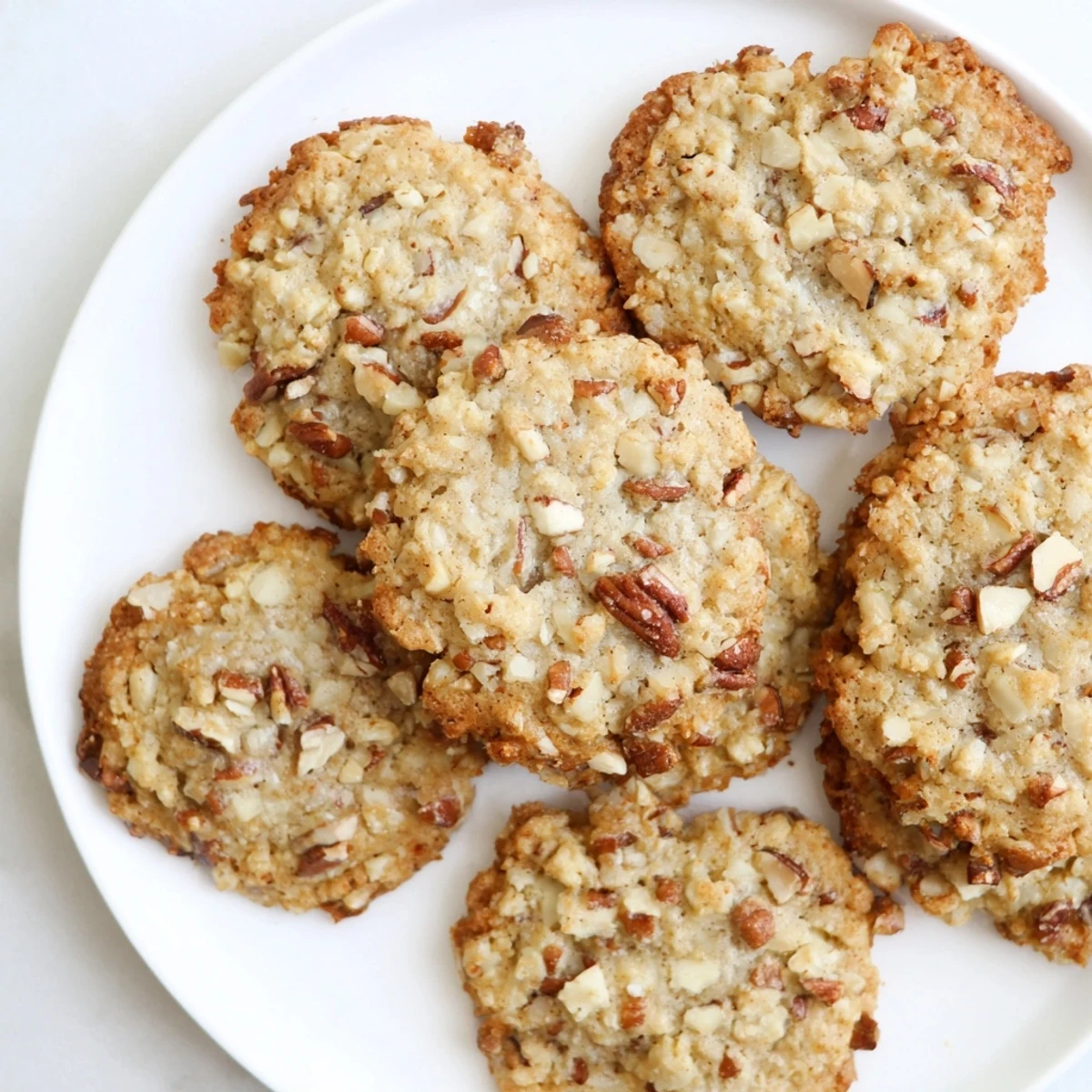 Close-up of keto maple pecan crunch cookies topped with coarsely chopped pecans and golden baked surfaces