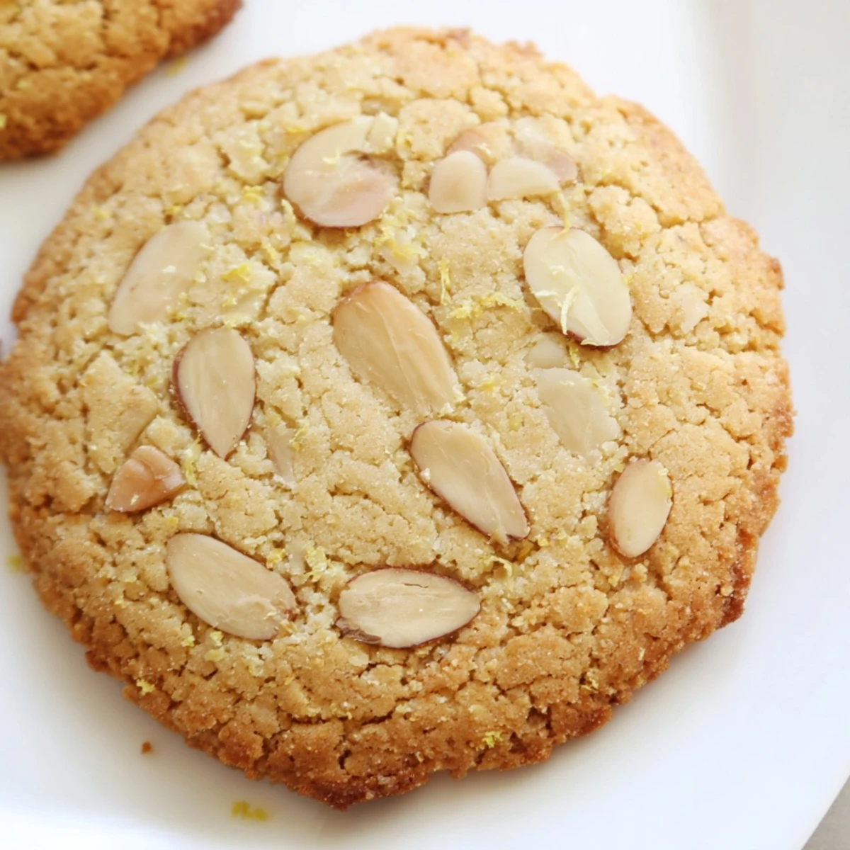 Round gluten-free lemon almond crisp cookies with golden edges cooling on a wire rack