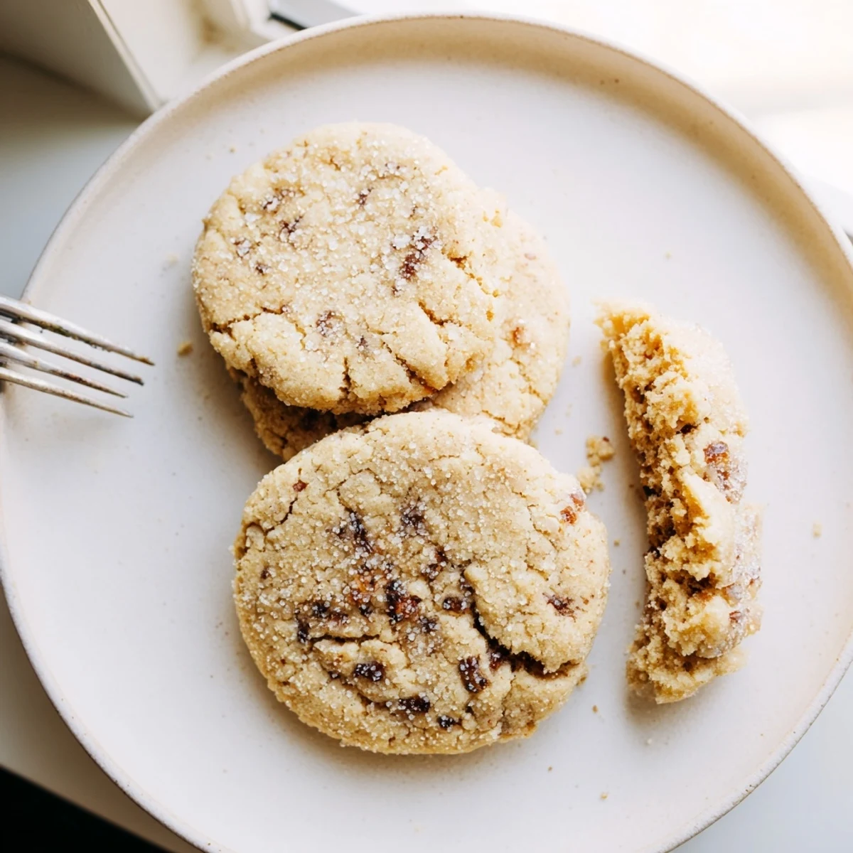 Golden vegan vanilla fig sugar cookies with crackled tops on a rustic parchment-lined baking sheet.
