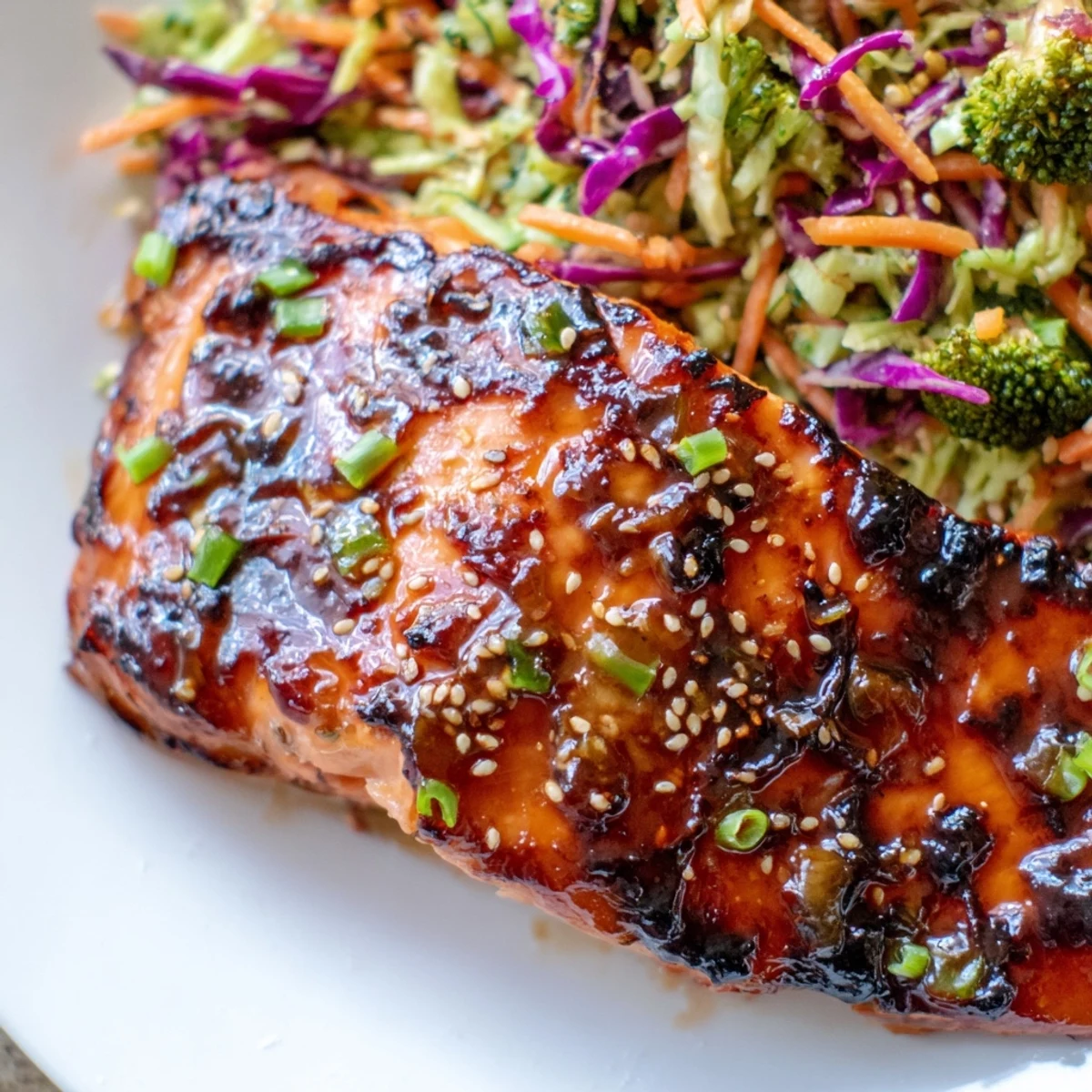 Crispy-edged miso maple salmon plated over vibrant sesame broccoli slaw with shredded carrots