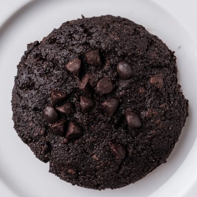 Close-up of New Year Celebration Mocha Whisper Keto Cookies with espresso powder specks, resting on parchment paper next to a steaming mug of keto hot chocolate.