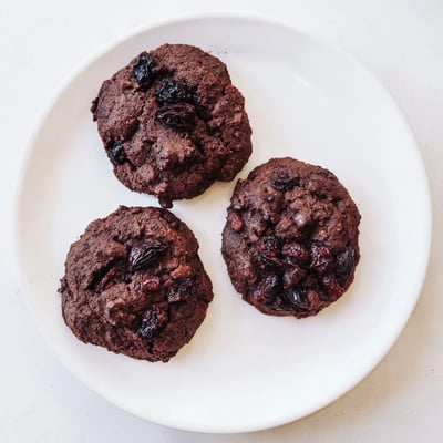 Gluten-free dark chocolate cherry cookies arranged on a wire cooling rack after baking with a soft chewy texture.