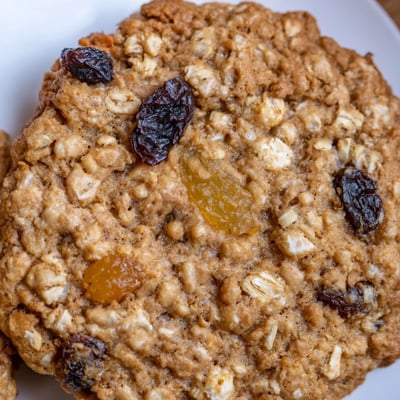 A close-up of Ginger Peach Oatmeal Raisin Cookies featuring dried peaches, plump raisins, and candied ginger.