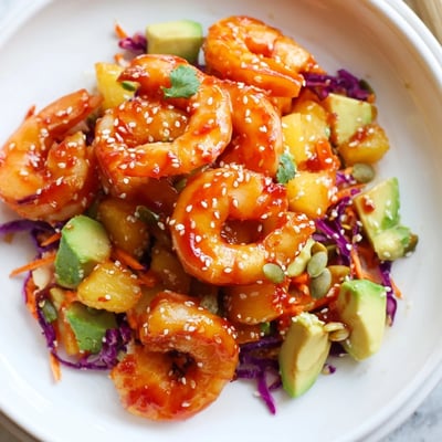 Golden caramelized shrimp with pineapple chunks served over crisp colorful lime avocado slaw